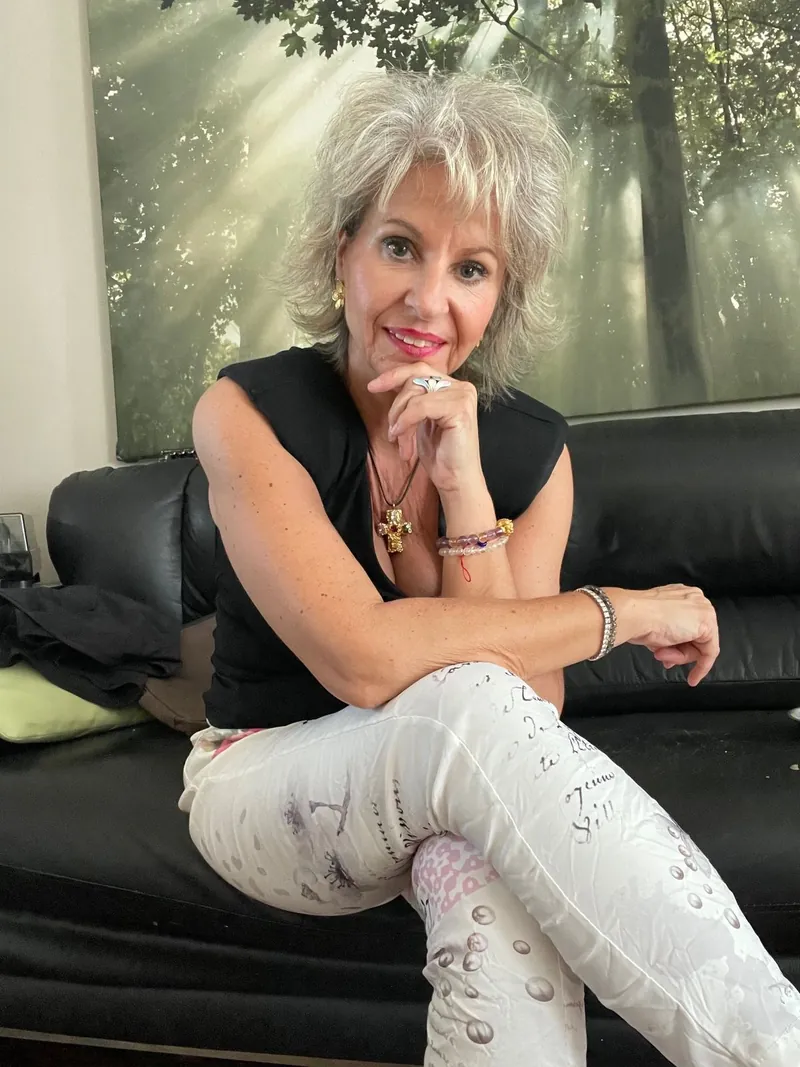 Luciana Stan seated on a sofa in front of a forest mural