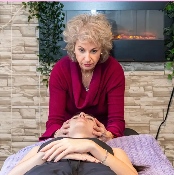 Luciana Stan giving a gentle hands-on treatment to a client resting on a treatment table